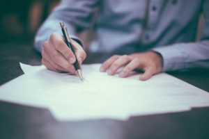 a person holding a pen and writing for Pennsylvania General Liability Insurance